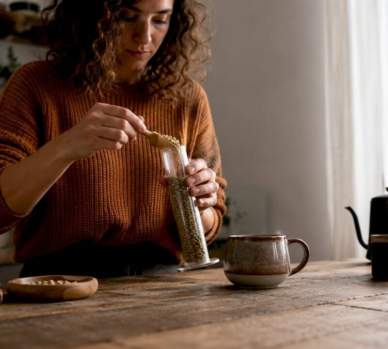 Home barista weighing green coffee beans at kitchen table